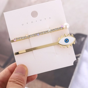 Set de horquillas doradas con pedrería, perla blanca y dijes de ojo turco azulado