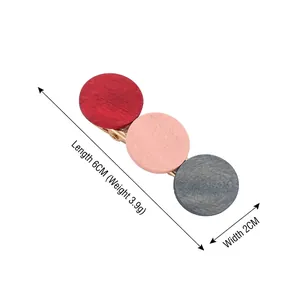 Minimalist geometric wooden hair clip with red and pink color block design on a metal base