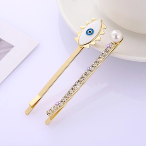 Set de horquillas doradas con ojo de esmalte, pedrería brillante y detalle de perla fina