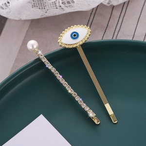 Evil eye hair clip set with rhinestones and faux pearls on a vintage green ceramic tray