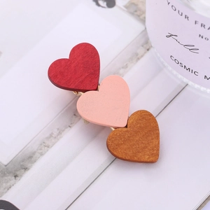 Detail of three-heart wooden hair clip in red, pink, and tan with gold metal base