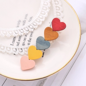 Detailed macro view of colorful wooden heart hair clips on a white ceramic plate