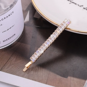 Elegant gold hair clip with sparkling rectangular zircons on a white ceramic plate