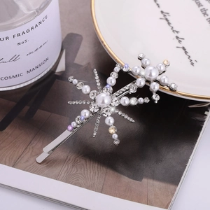 Elegant silver snowflake hair clip with pearls and rhinestones on a white ceramic tray