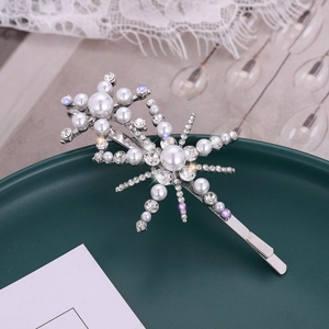 Elegant silver snowflake hair clip with pearls and rhinestones on a green plate