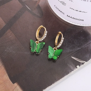 Détail de boucles d'oreilles créoles dorées avec papillons verts marbrés et cristaux pavés
