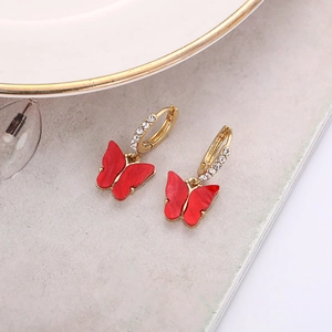Détail des boucles d'oreilles papillon rouge avec strass et anneaux dorés brillants