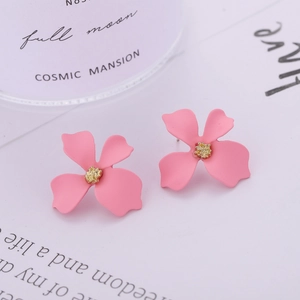 Macro shot of pink four-leaf flower earrings with golden stamen on a white card