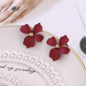 Detailed macro view of matte red floral earrings with gold stamens on a lace decorative plate
