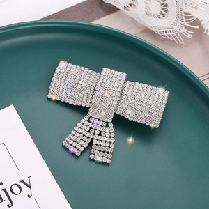 Barrette nœud élégante avec strass scintillants et cristaux colorés sur une assiette verte