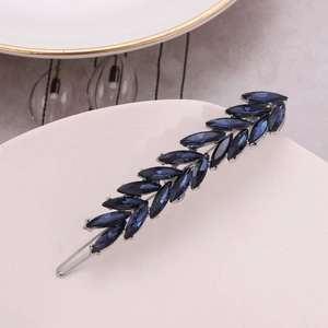 Détail d'une pince à cheveux en cristal bleu en forme de feuille sur plateau en céramique
