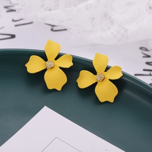 Detailed macro view of yellow four-petal flower earrings with a matte lacquer finish