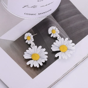 Détail de boucles d'oreilles marguerites à double couche avec pétales blancs et cœur jaune