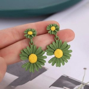 Boucles d'oreilles marguerite vert mat à double couche présentées sur un doigt