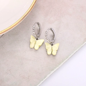 Close-up of silver hoop earrings featuring fine rhinestones and a yellow butterfly pendant