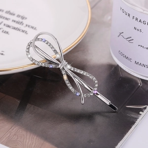 Barrette à cheveux nœud argenté avec strass brillants sur un fond de style minimaliste
