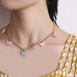 Modieuze gouden ketting met vijf kleurrijke vlinders van acetaat gedragen door een model