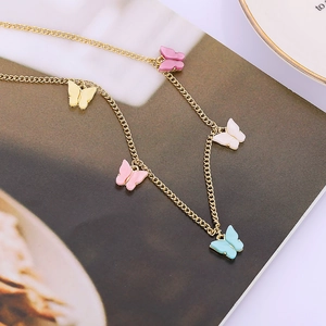 Detailweergave van gouden vlinderketting met kleurrijke pastelhangers op een dienblad