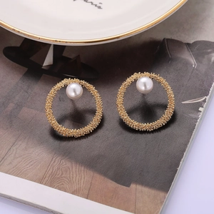 Detailed view of luxury gold C-shape stud earrings with white pearl and grainy metal texture