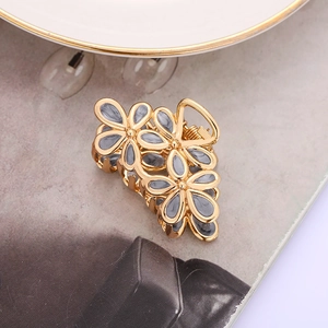 Detailed macro view of gold metal floral hair claw clip with marble enamel inlay