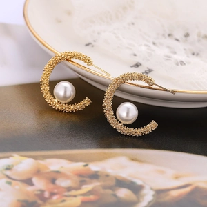 Elegant C-shaped gold textured earrings featuring white pearls in luxury French style