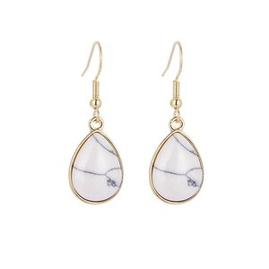 Detail van witte marmeren druppeloorbellen met elegante gouden metalen haken