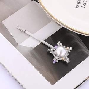Barrette étoile argentée avec cristaux et perle sur un fond de magazine minimaliste