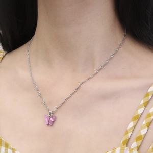 Collier à pendentif papillon violet avec chaîne argentée sur le cou du modèle