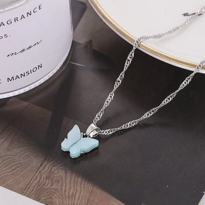 Collier chaîne argentée avec un pendentif papillon bleu clair givré en détail