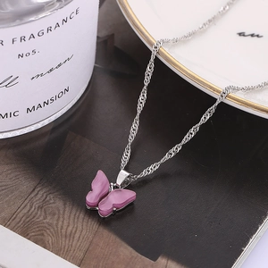 Gros plan d'un pendentif papillon violet avec chaîne ondulée argentée sur un décor chic