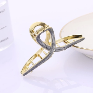 Elegant gold metal hair claw clip with grey marble texture in a minimalist geometric design