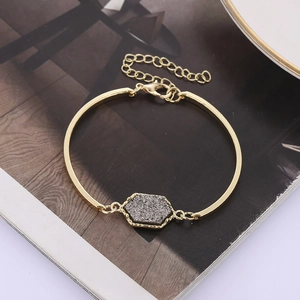 Detail of a gold hexagon druzy bracelet with lobster clasp on a stylish magazine