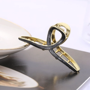 Detail of cross geometric hair claw clip with golden metal finish and black marble texture