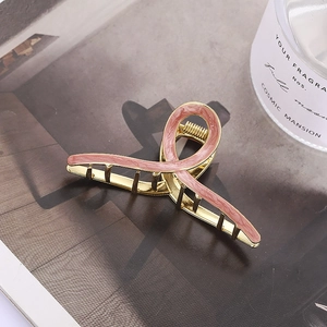 Detail of elegant gold metal hair claw clip with pink marble textured geometric cross pattern