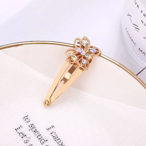 Pinza de pelo de mariposa dorada con diamantes de imitación morados y blancos sobre tela