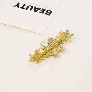 Détail macro de la pince à cheveux flocon de neige dorée montrant le clip à ressort