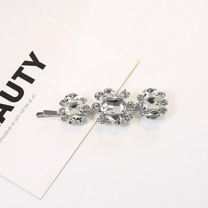 Silver hair clip with sparkling rectangular crystals and rhinestones on white surface