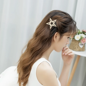 Elegante fermaglio per capelli a stella dorata con perle indossato su capelli ricci fini