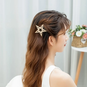 Elegante fermaglio per capelli a stella dorata con strass e perle sul profilo di donna
