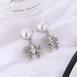 Elegant silver bow earrings with colorful rhinestones and white pearl on white fabric