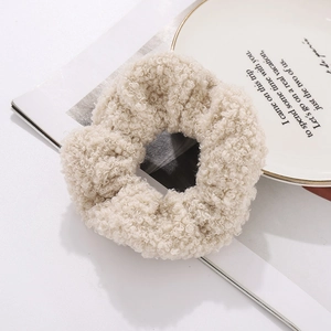 Close-up of soft beige faux shearling hair scrunchie with plush curly wool texture