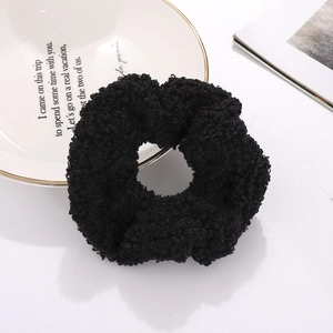 Plush black faux lamb wool scrunchie accessory displayed on a stylish white plate