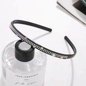 Elegant thin black headband with double-row sparkling rhinestones on a glass bottle