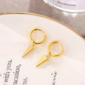 Close-up of golden hoop earrings with polished spike charms on a decorative porcelain plate