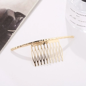 Minimalist gold metal hair comb with hammered texture and multi-tooth design in elegant setting