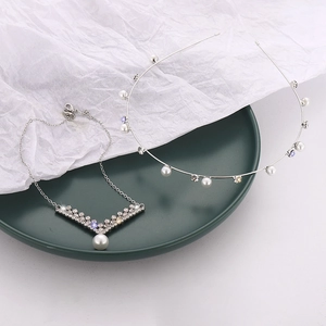 Detail view of pearl and rhinestone hairband with matching V-shape pendant necklace