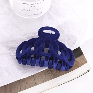 Detail of dark blue flocked hair claw clip with chain link design on white textured background