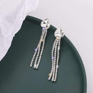 Boucles d'oreilles pendantes argentées avec cristaux en cœur et pompons sur assiette verte