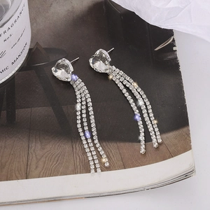 Détail macro de boucles d'oreilles cœur en cristal argenté avec de longues franges strass