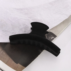 Detail of matte black flocked hair claw clip with curved long bar design for thick hair